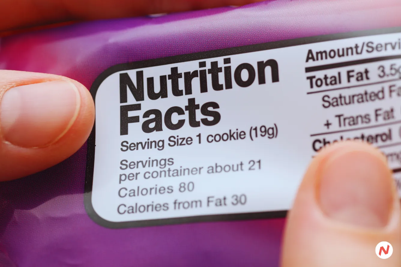Person reading a food label ingredients list to check for sugar, salt, and trans fat content